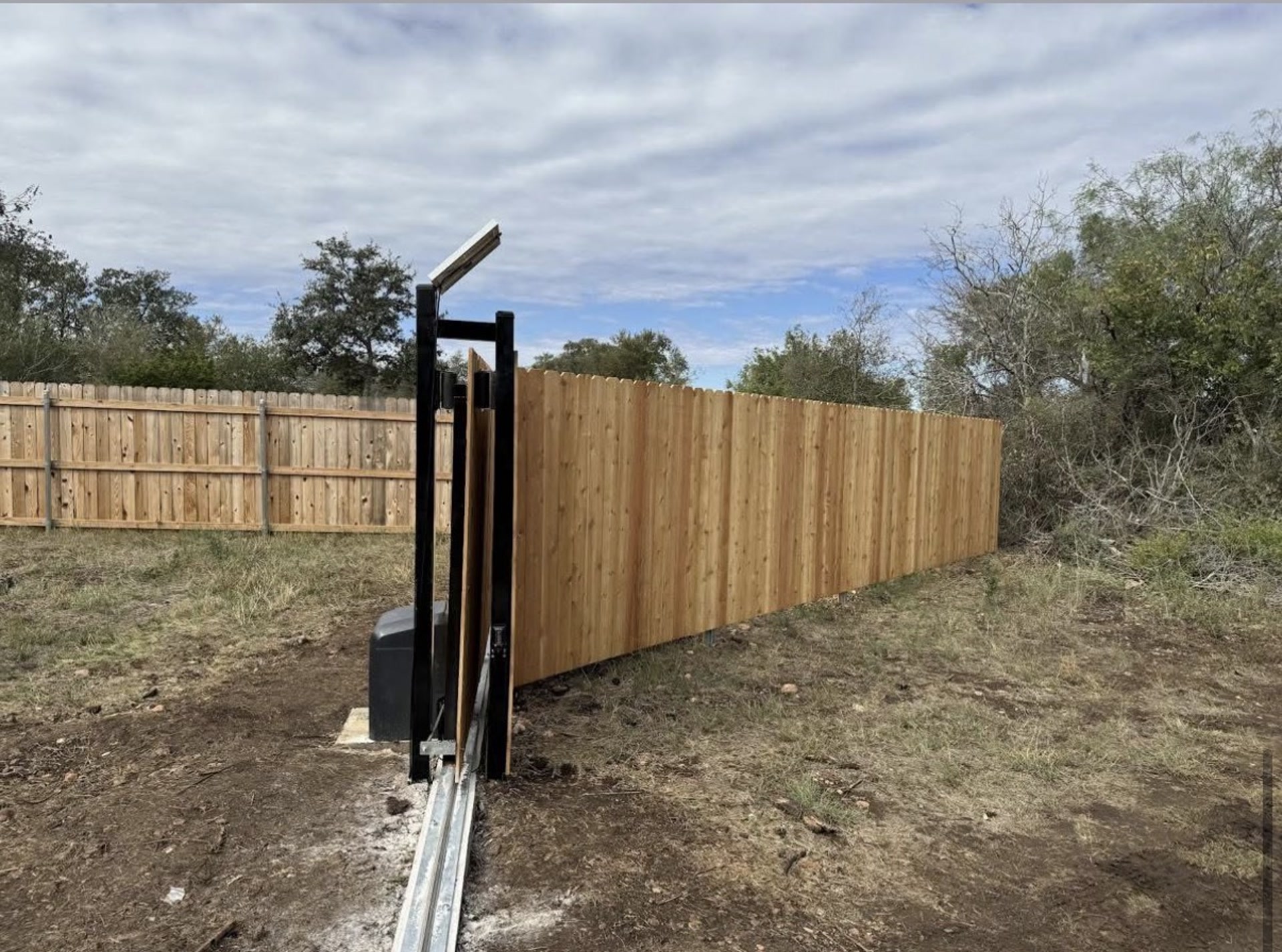 Automatic driveway gate opener beside a new cedar privacy fence
