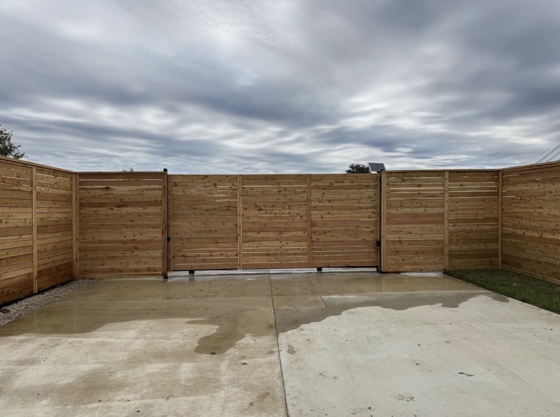 Horizontal cedar privacy fence with double drive gate on a concrete pad