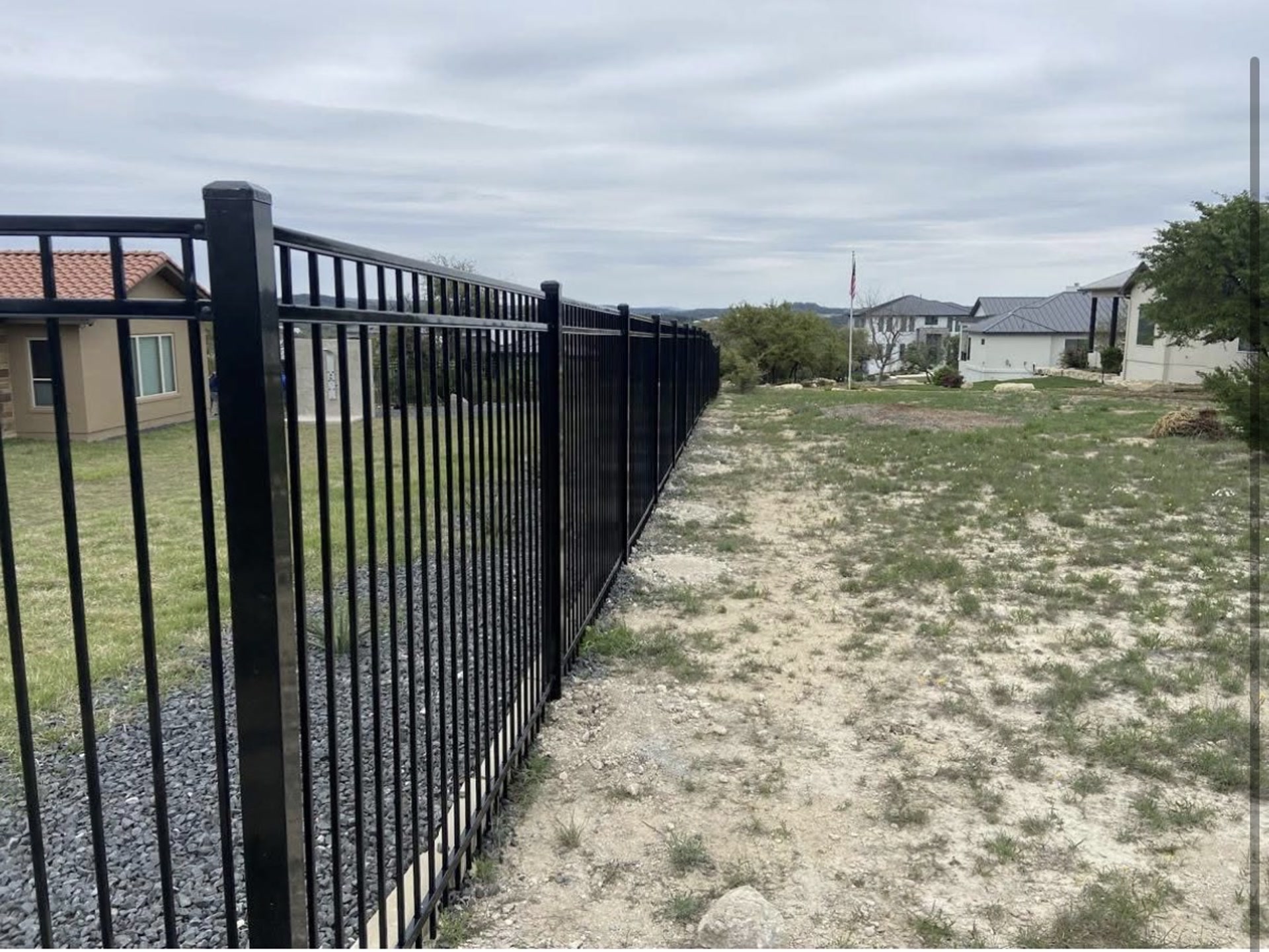 Black iron fence line along a Hill Country property